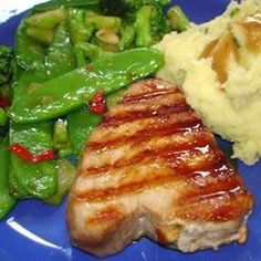 a blue plate topped with meat and veggies next to mashed potatoes, broccoli