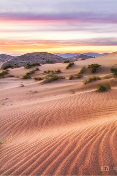 the sun is setting over sand dunes in the desert