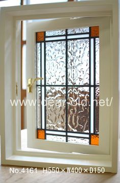 an open window with decorative glass on the outside and inside, in front of a wooden floor