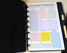 a personal organizer is open on top of a desk with pen and notepad next to it