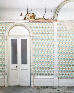 an empty room with a white door and wallpaper on the walls that has been torn off