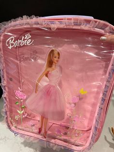 a barbie doll in a pink dress on a plastic case with flowers and butterflies around it