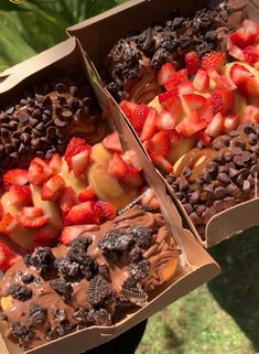 two boxes filled with chocolate covered strawberries and other desserts next to each other