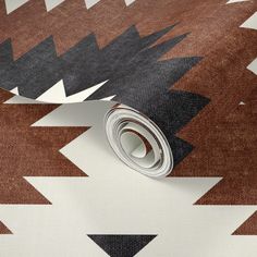 a roll of brown and white fabric on top of a wallpaper with an arrow pattern