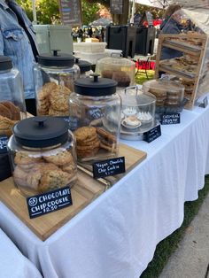 a table topped with lots of cookies and desserts under a tented awning