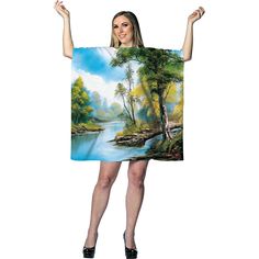 a woman is holding up a painting on the back of a towel that has a river and trees in it