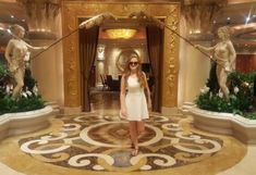 a woman in a white dress standing in front of some statues on the floor at a hotel