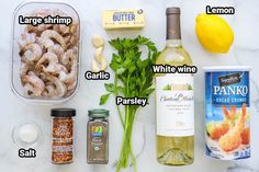 ingredients to make shrimp salad laid out on a white marble counter with lemons, garlic, parsley, butter, and seasoning