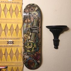 a skateboard hanging on the wall next to a shelf with a painting on it