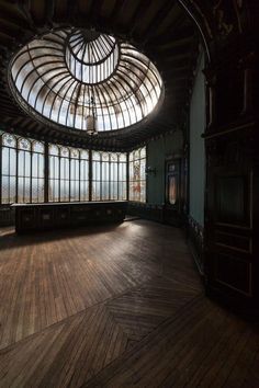 an empty room with wooden floors and large windows on the ceiling is lit by sunlight