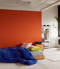 a bedroom with an orange wall and blue sheets on the bed in front of it