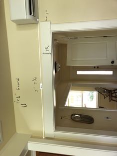 the inside of a kitchen with white cabinets and an open door to another room that has a window in it