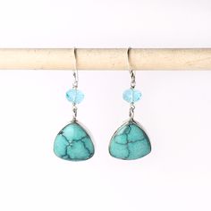 "These handmade earrings are of natural turquoise hand carved trillion cabochons bezel set in sterling silver. Above the turquoise is a bright blue faceted apatite bead. The earrings have a drop length of 1 1/2\" inch. Handmade in the USA. Dimensions: Each side of the triangle is 16mm. The apatite are 6mm. Drop length of 1 1/2\" inch. ❤️ Visit my shop: https://www.etsy.com/shop/JanPalomboDesign ❤️Click link below to see more earring designs: https://www.etsy.com/shop/JanPalomboDesign?section_id= Turquoise Teardrop Faceted Earrings, Turquoise Faceted Drop Earrings, Turquoise Faceted Teardrop Earrings, Turquoise Teardrop Faceted Jewelry, Faceted Turquoise Teardrop Earrings, Turquoise Sterling Silver Earrings With Gemstone Accents, Turquoise Drop Earrings With Gemstone Accents, Turquoise Gemstone Drop Earrings, Turquoise Aquamarine Dangle Earrings