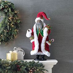 a santa clause figurine sitting on top of a mantle next to a wreath