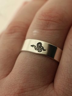 "One of our favorites, this beautiful ring features a detailed magical snake for everyday wear. DETAILS: -Each ring is hand stamped -Ring is Sterling Silver, Fine Silver, or 14k Gold Filled -6mm ring You will receive one hand-stamped ring filled with a black enamel finish. **Every item is handmade, this means that each will be unique and may not look EXACTLY like the picture, but it will look very similar ➡ORDER PROBLEMS If there are any problems with your order please contact me, my goal is for Symbolic Adjustable Snake Ring For Anniversary, Engraved Snake Ring Open Design For Gift, Engraved Open Snake Ring For Gift, Engraved Snake Shape Ring For Gift, Snake Shaped Engraved Rings For Gifts, Adjustable Engraved Snake Ring Gift, Spiritual Snake Ring As Gift, Symbolic Engraved Snake Ring As Gift, Symbolic Adjustable Engraved Snake Ring