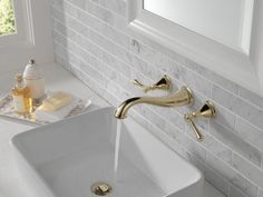 a white sink with gold faucet and soap dispenser next to it