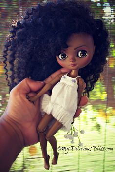 a hand holding a doll that is wearing a white dress