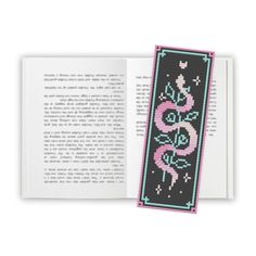 an open book with a cross stitch pattern on the front and back cover in pink