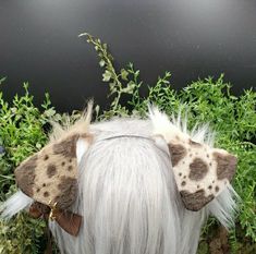 the back of a white haired woman's head with brown and white feathers on it