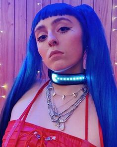 a woman with blue hair wearing a light up choker and chain around her neck