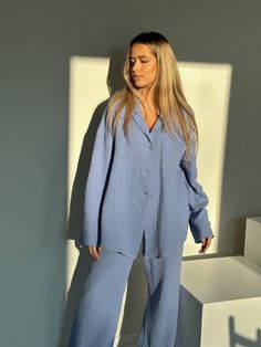 "Our women's loungewear set is the epitome of comfort and style. Made from 100% organic cotton muslin, it offers a lightweight, natural texture that not only feels incredibly soft against your skin but also drapes elegantly. The oversized shirt and high-waisted trousers create a perfect balance between fashion and relaxation, making it ideal for your leisure time or a getaway. With its handmade quality, breathable fabric, and the added convenience of pockets in the pants, this loungewear set is Solid Color Relaxed Sleepwear, Oversized Long Sleeve Cotton Sets, Comfortable Oversized Loungewear Sleepwear, Relaxed Fit Blue Sleepwear For Relaxation, Blue Relaxed Fit Lounging Sets, Oversized Cotton Sleepwear In Relaxed Style, Relaxed Fit Sleep Sets, Blue Relaxed Fit Loungewear Sets, Solid Color Oversized Loungewear Sets