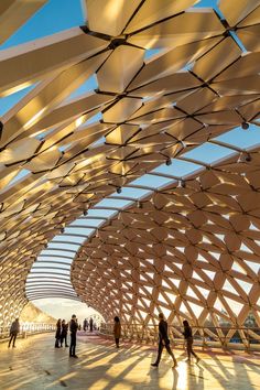 people are walking around in an open area with large wooden structures on the ceiling and walls