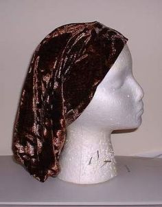 a white mannequin head wearing a brown and gold turban on it's head