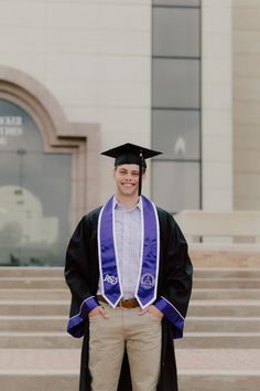 a man wearing a graduation cap and gown standing in front of steps with his hands on his hips