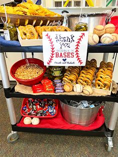 a table filled with lots of food on top of a red tray next to a sign that reads base ball bases