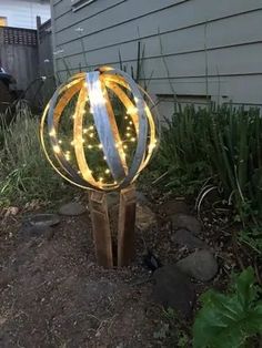 a light up ball sitting in the middle of a yard next to some grass and bushes