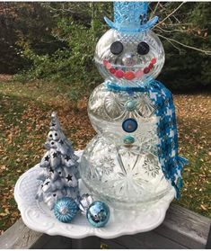 a glass snowman sitting on top of a white plate