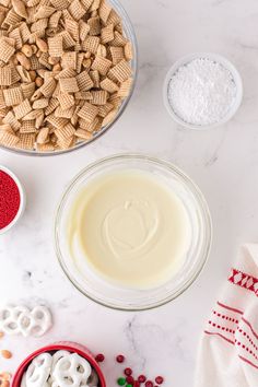 ingredients to make christmas crackers laid out on a white marble counter top, including milk, sugar, and pretzels