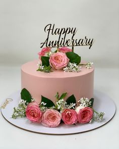 there is a pink cake with flowers on the top that says happy anniverary