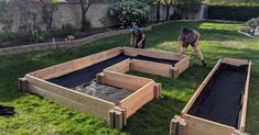 two men working in the backyard with raised beds and sandpits on the grass