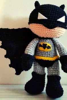 a crocheted batman doll is posed on a table next to a white wall