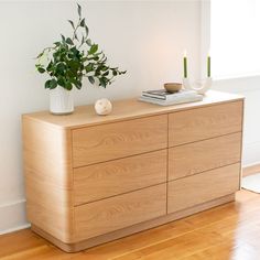 a wooden dresser sitting on top of a hard wood floor next to a white wall