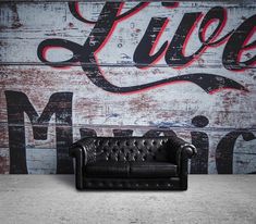 a black leather couch sitting in front of a wall with the word live music painted on it