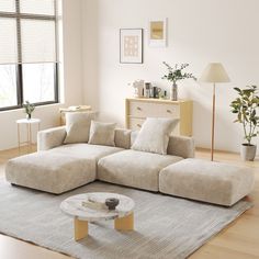 a living room with a large sectional couch and coffee table in front of the window