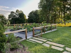 an outdoor garden is shown in the middle of a grassy area with stepping stones and wooden railings