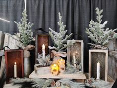 some candles are sitting on a table with pine branches and other items around it,