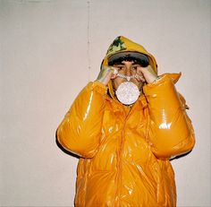 a man in a yellow jacket holding a white object to his face