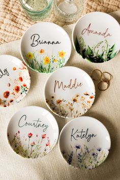 four personalized dishes with flowers on them and two wedding rings in the middle one