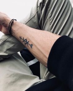 a man with a cross tattoo on his arm holding onto a jacket while sitting down