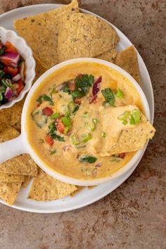 a white plate topped with tortilla chips next to a bowl of salsa and guacamole