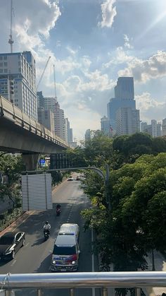 cars are driving down the street in front of tall buildings and skyscrapers on a sunny day