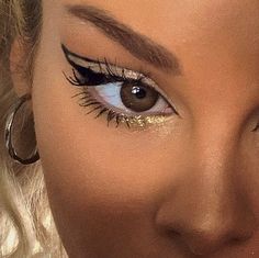 a close up of a woman's face with long lashes and gold glitter on her eyes