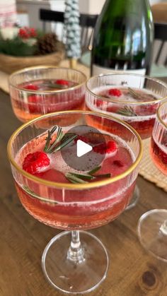 three glasses filled with liquid and garnish sitting on top of a wooden table