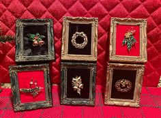 four framed christmas ornaments are sitting on a red tablecloth with gold trimmings