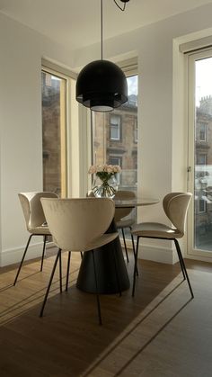 a dining room table with chairs and a vase filled with flowers on top of it