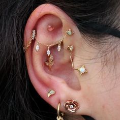 a woman with ear piercings on her ears and behind the ear is a rose